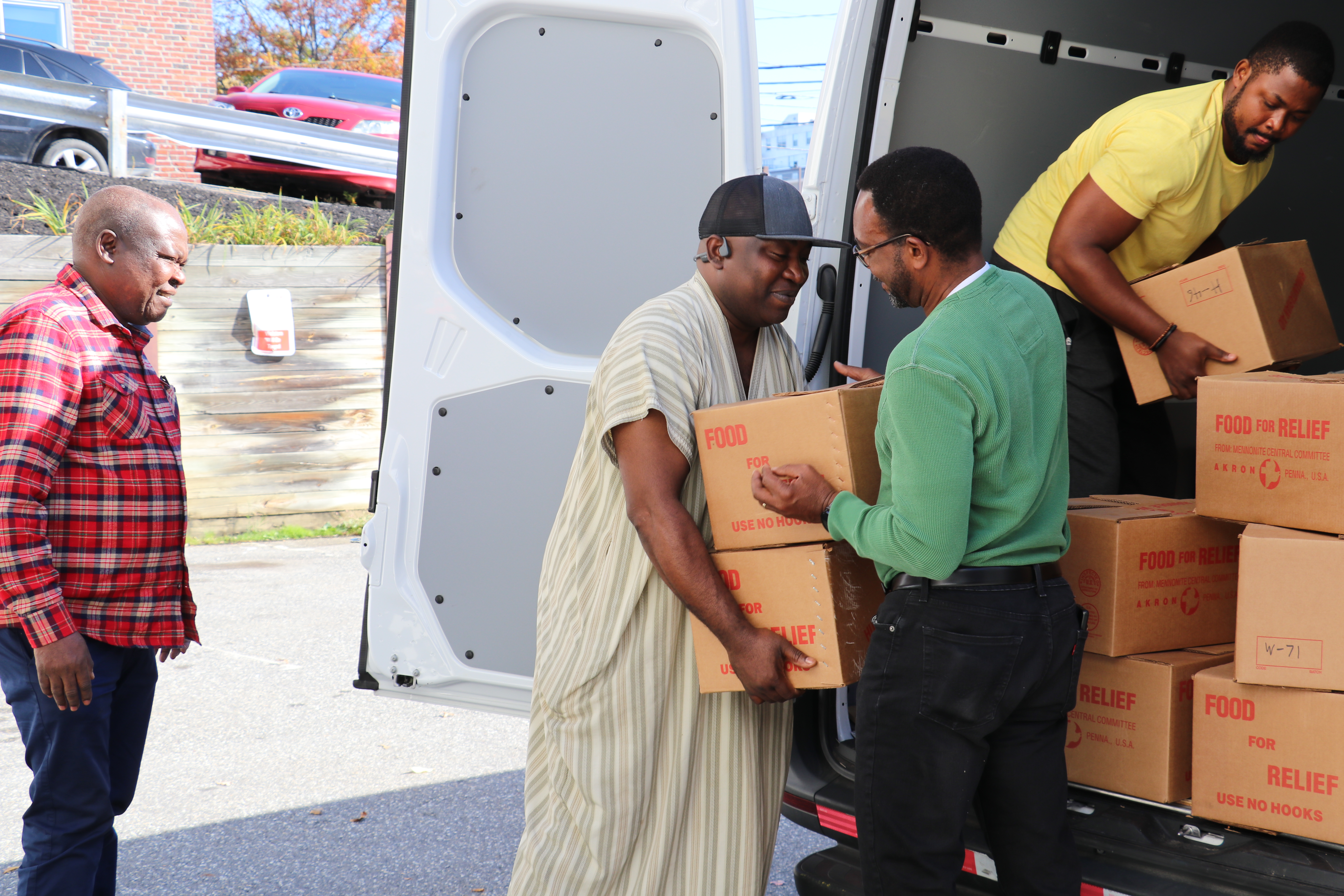 men unload boxes of canned meat from a van