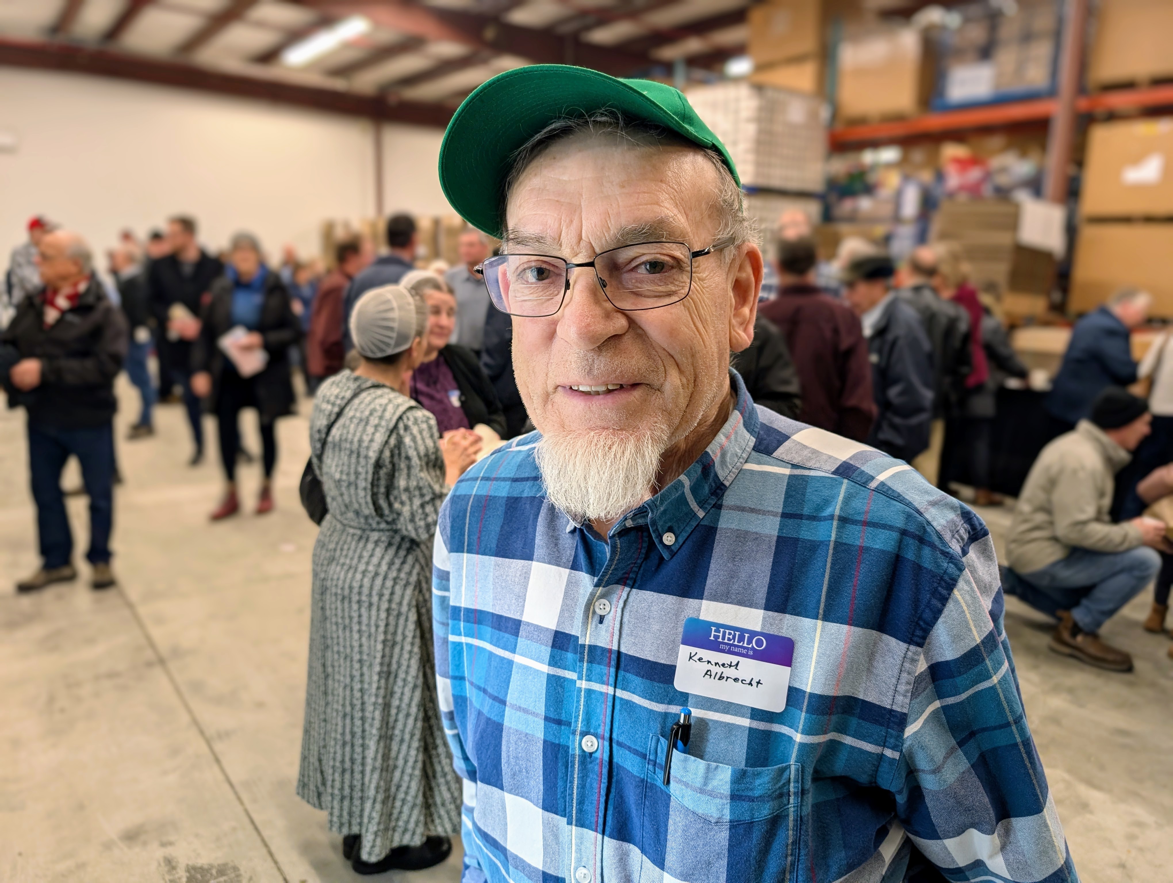 A older man wears a plaid shirt, hat, and glasses at the grand opening of the stationary cannery.