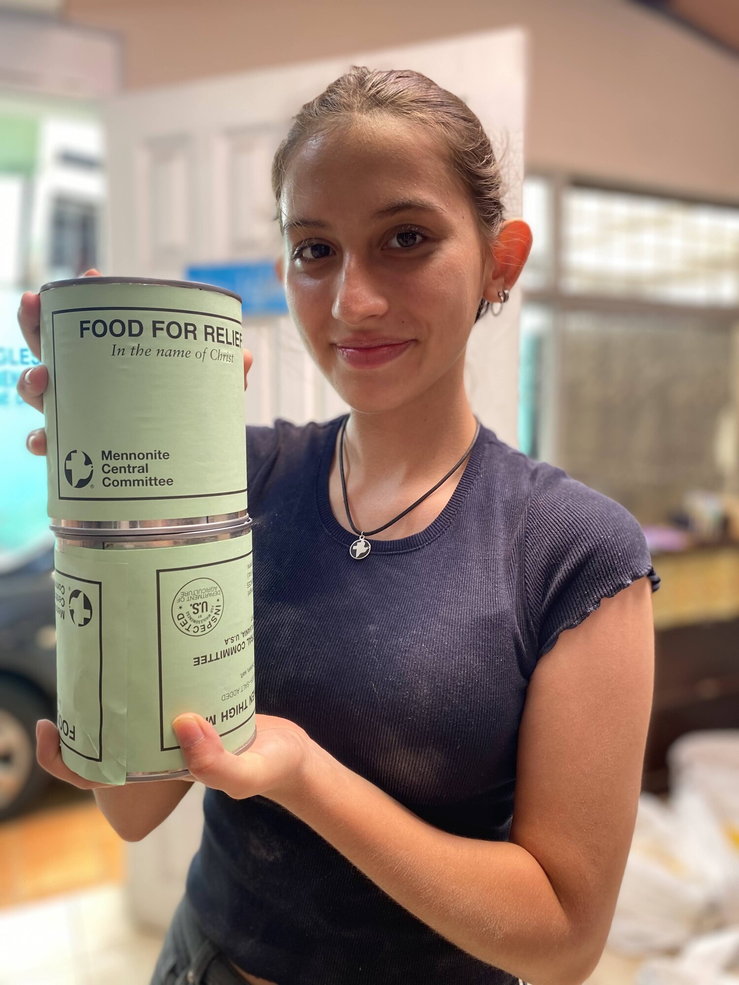 A young woman holding up cans of MCC meat