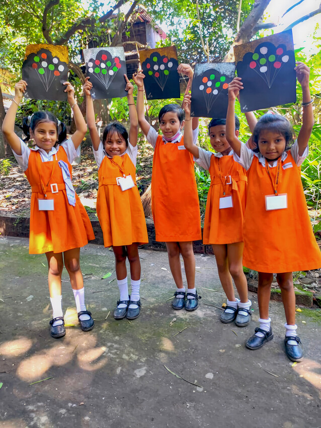 A group of school girls holding up artwork