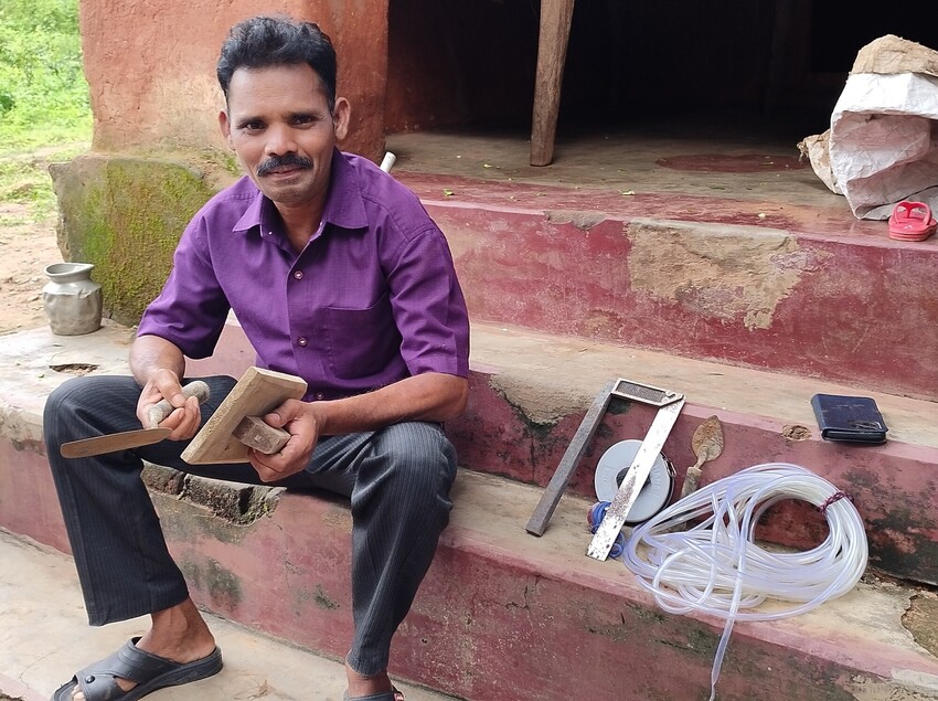 A man sitting on house steps holding tools from a masonry kit