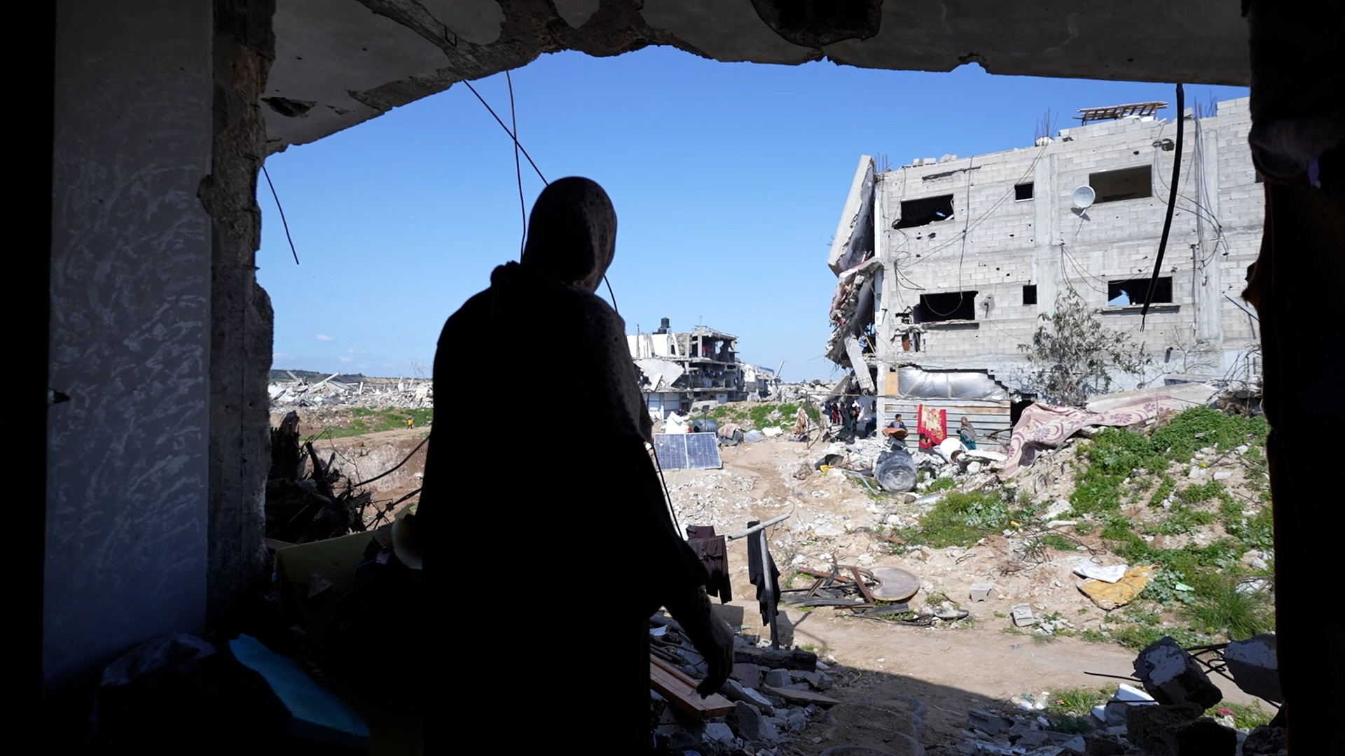 Woman looks out at destruction in front of her house.