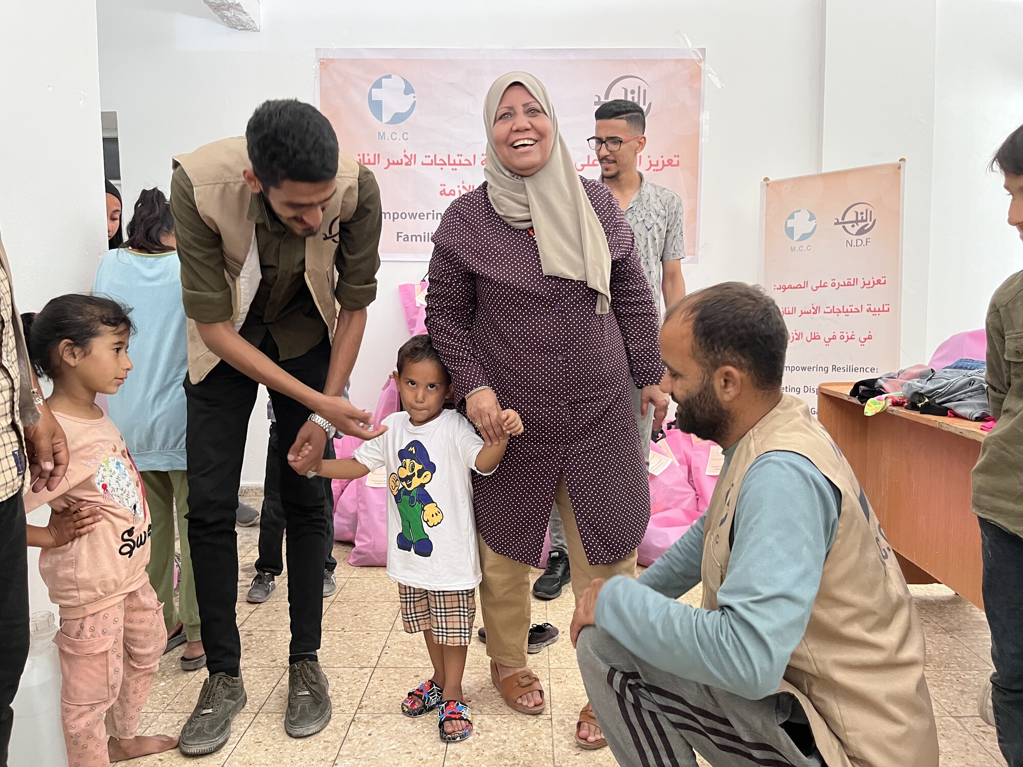 Woman smiling while holding hand of a child in a group of people looking at the child