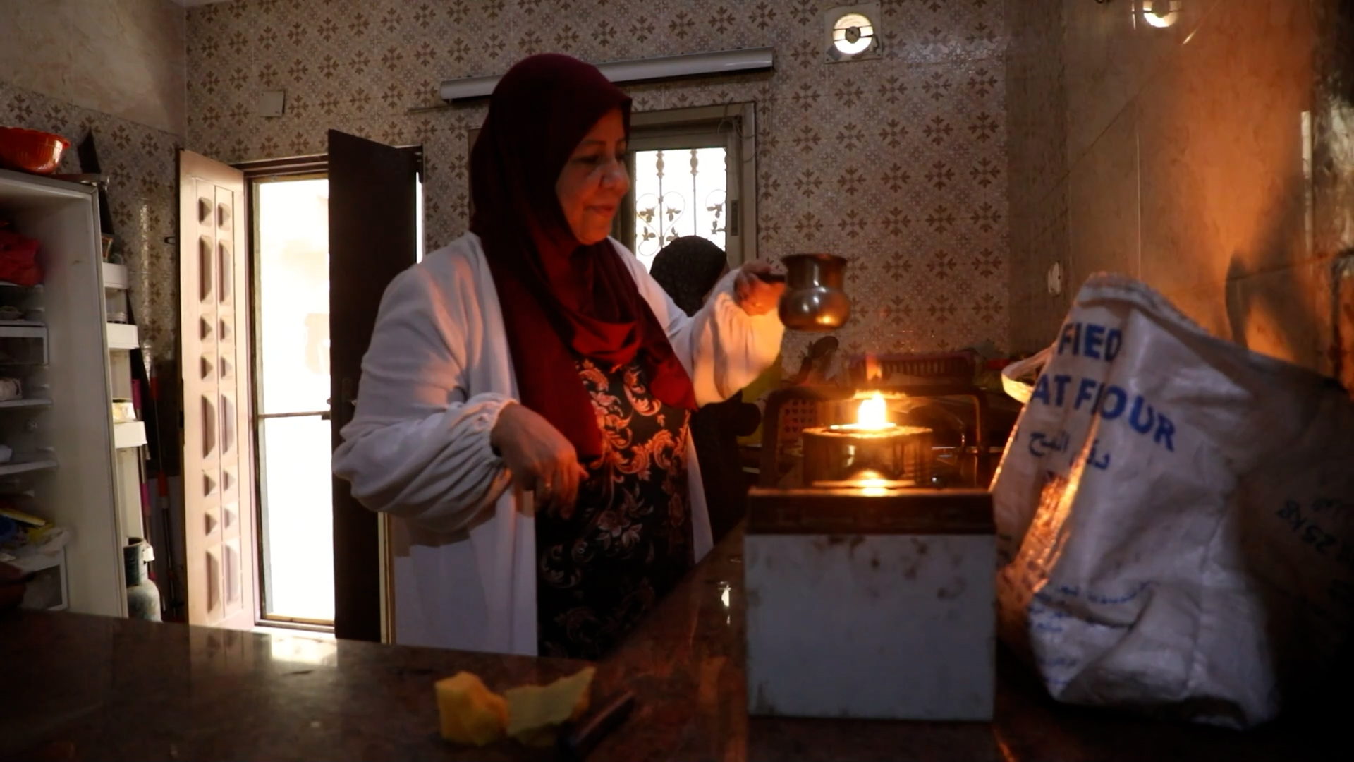 woman in dark room cooking over one-burner gas stove