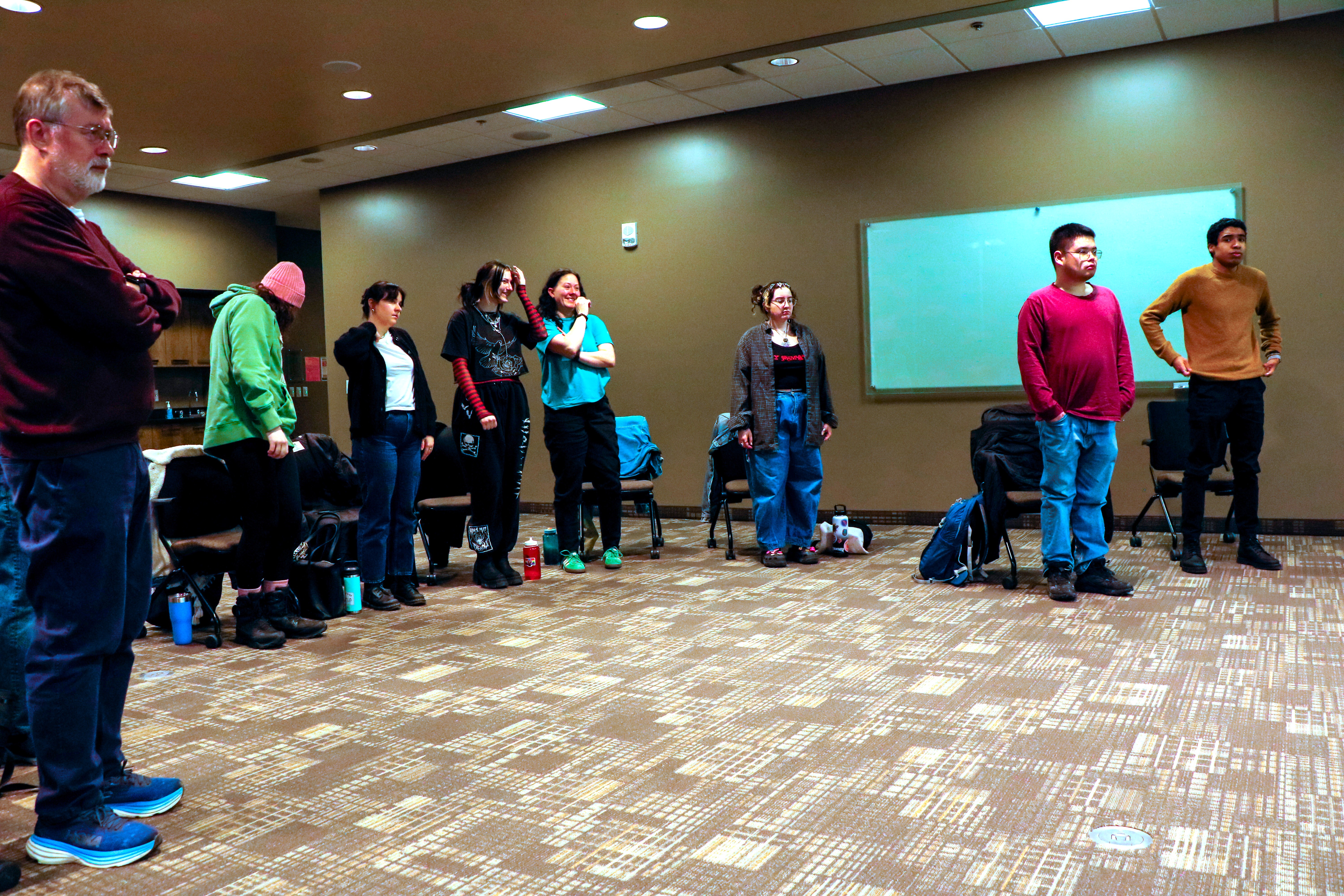 People gather in a meeting room and form a semi-circle and face the same direction.