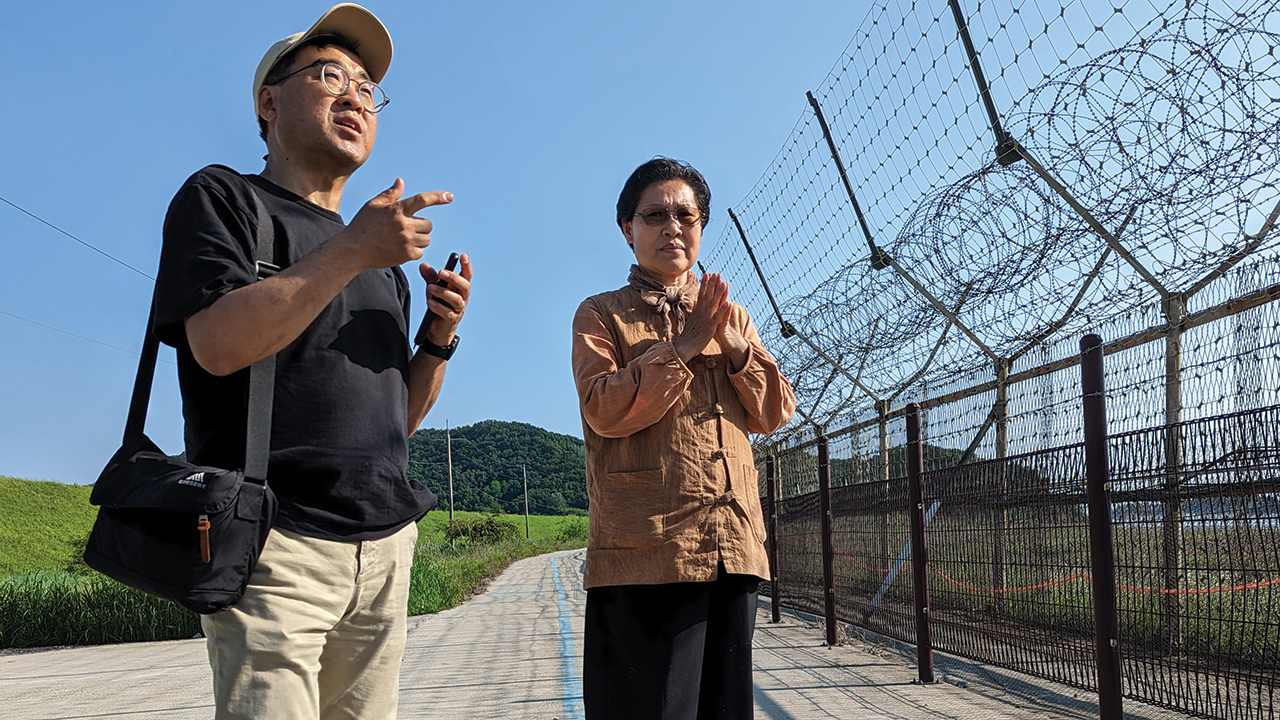 Two gentlemen standing next to a fence