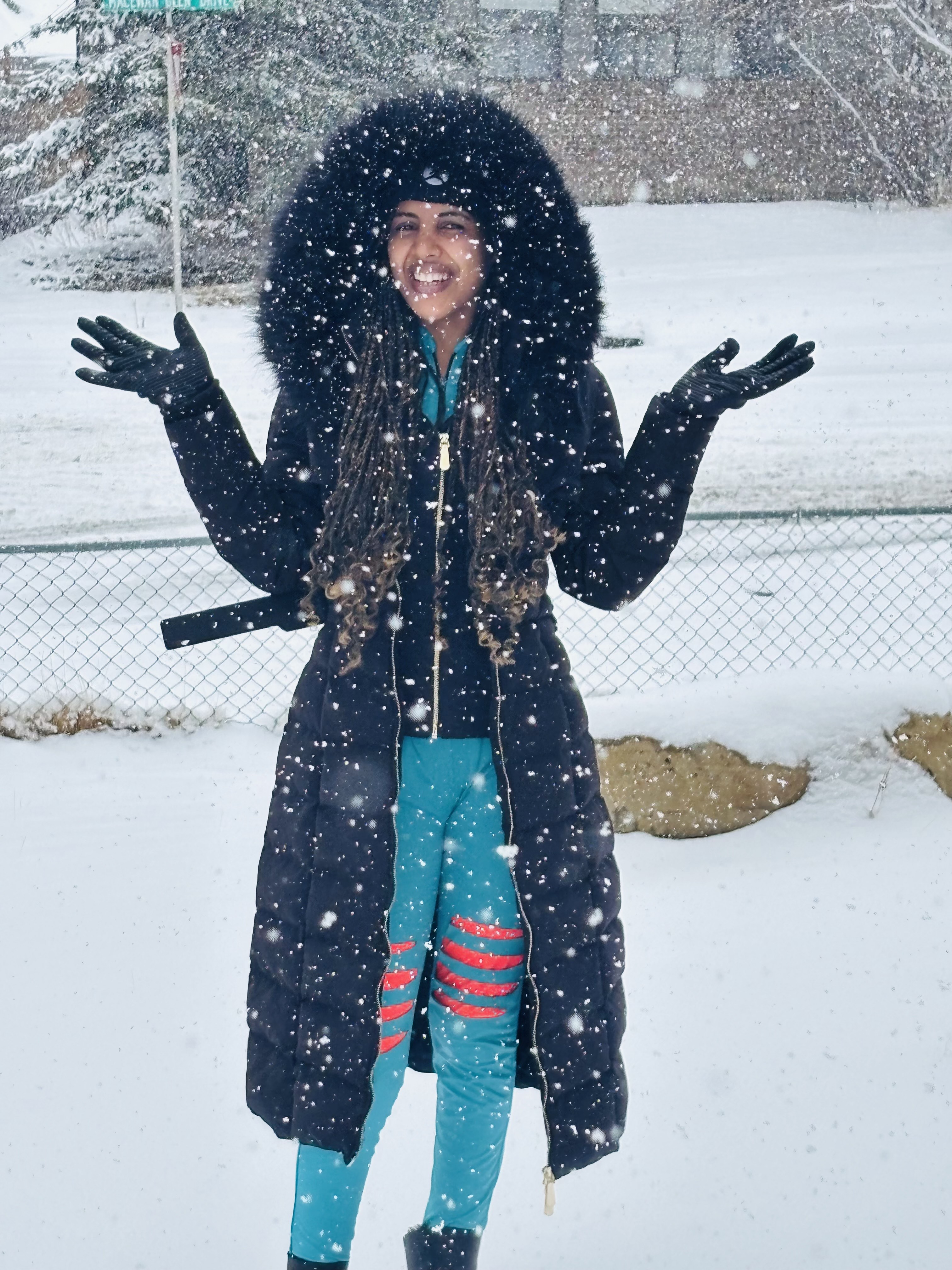 A young woman in a winter coat smiling for a photo with snow in the background