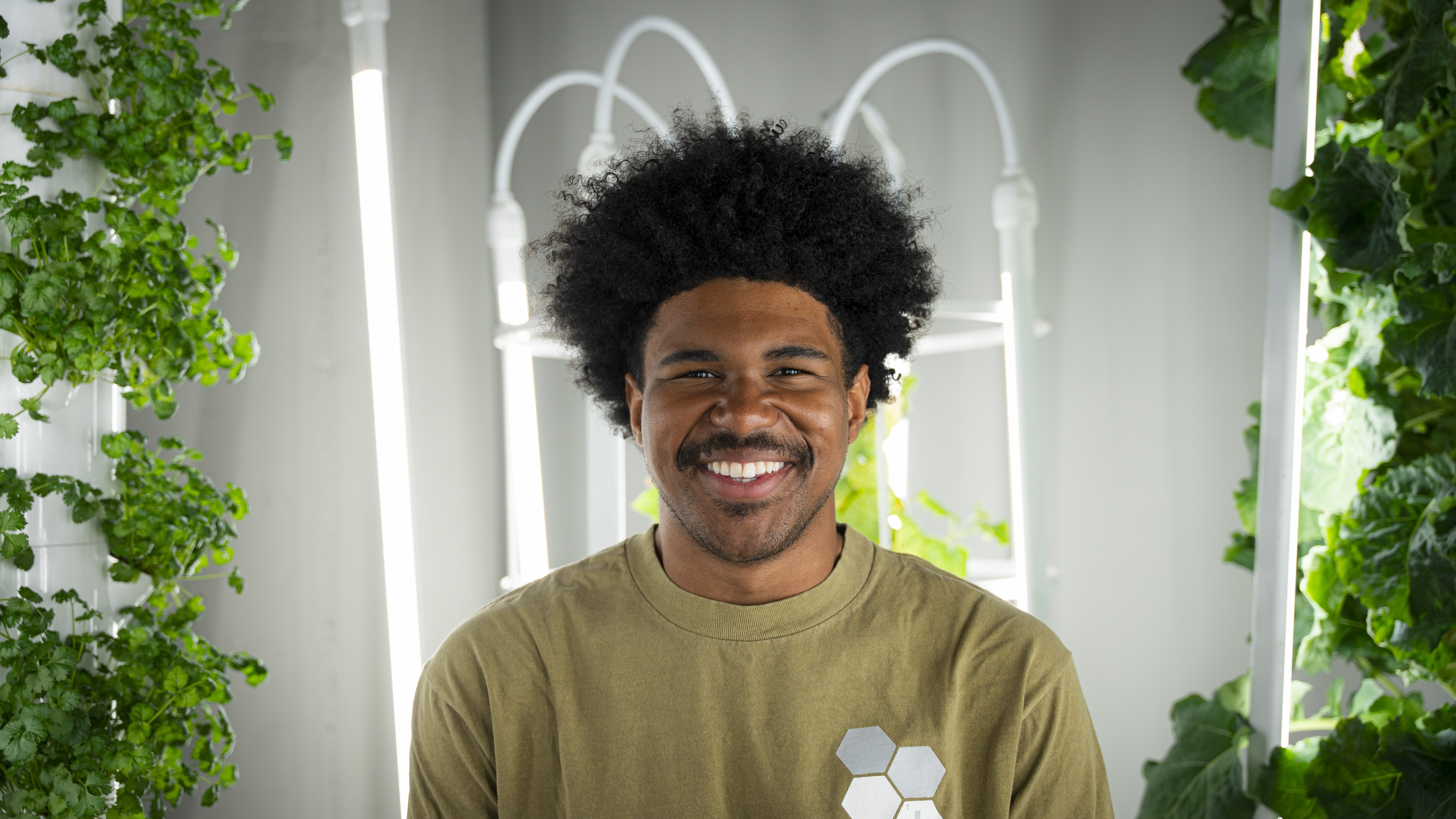 man smiles at camera for portrait with plants in the background