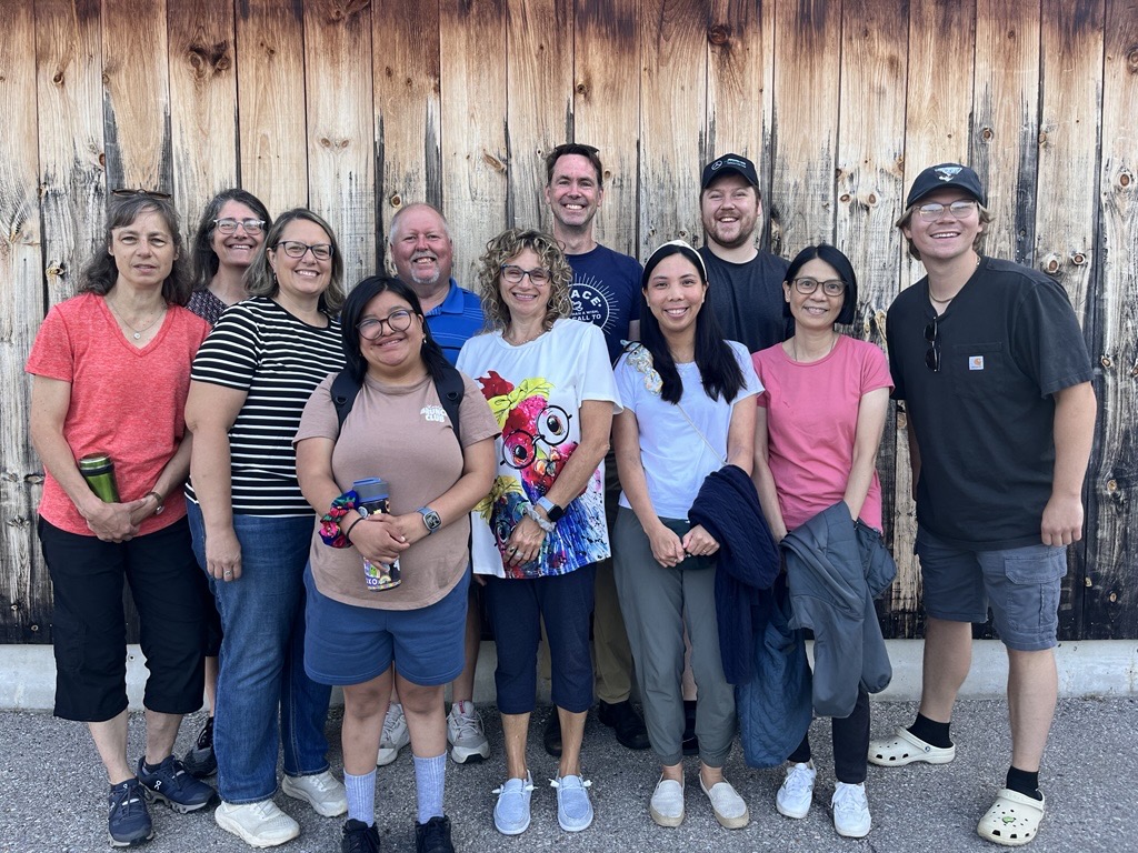 A group of people pose for a photo in front of a wooden panel background.