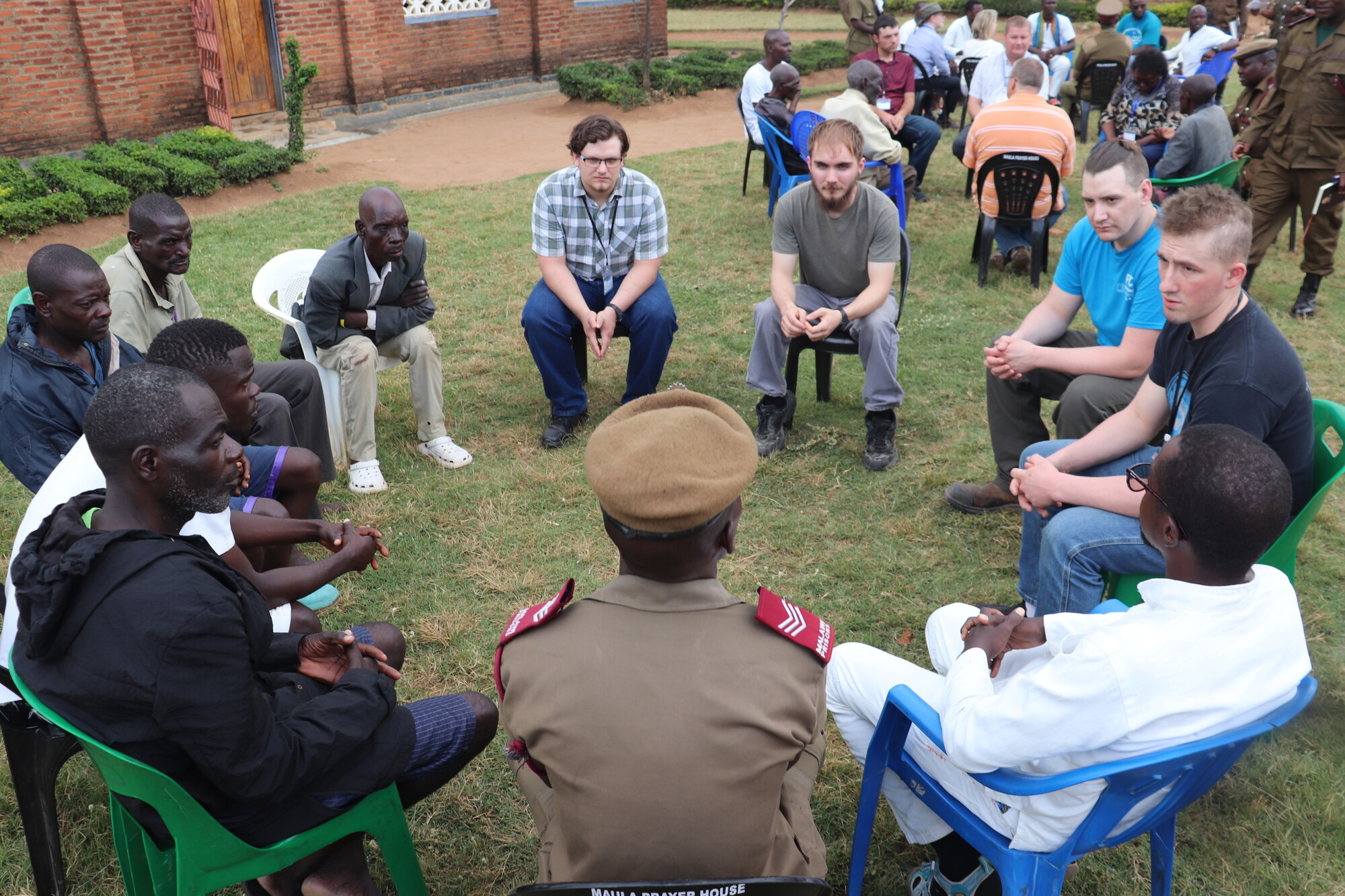 circle of men seated outside on a grassy lot
