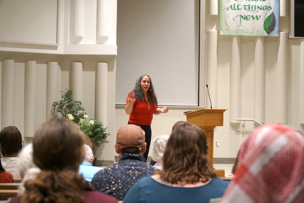 A woman speaking at the front of a church.
