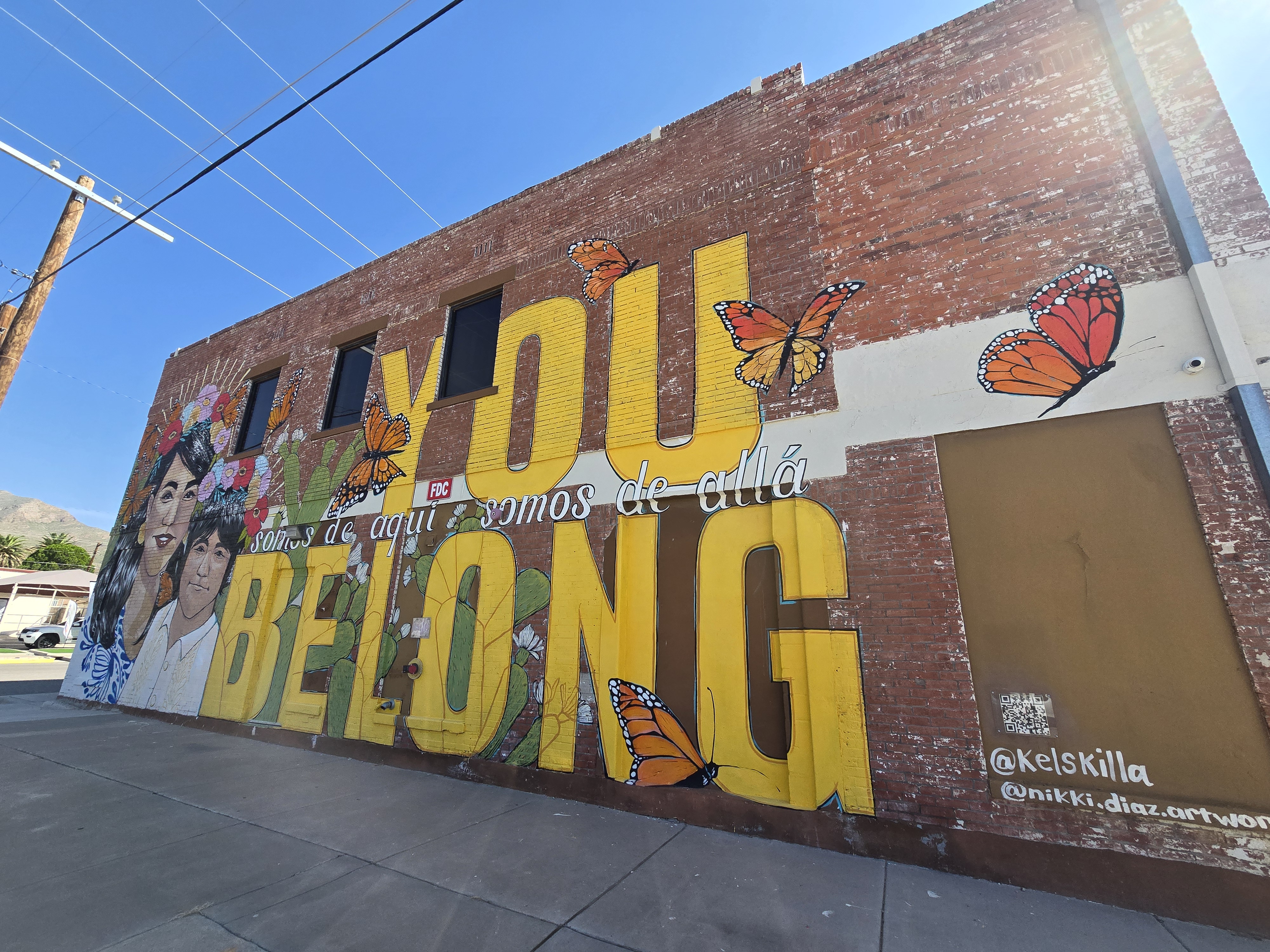 Mural of brick wall, with text "You belong, somos de que somos de alla"