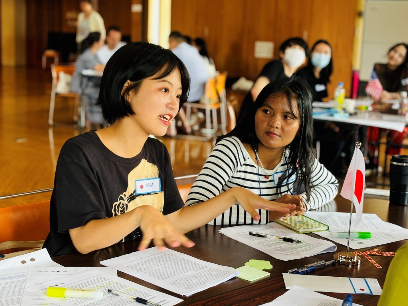 Two young women sitting at a table talking.