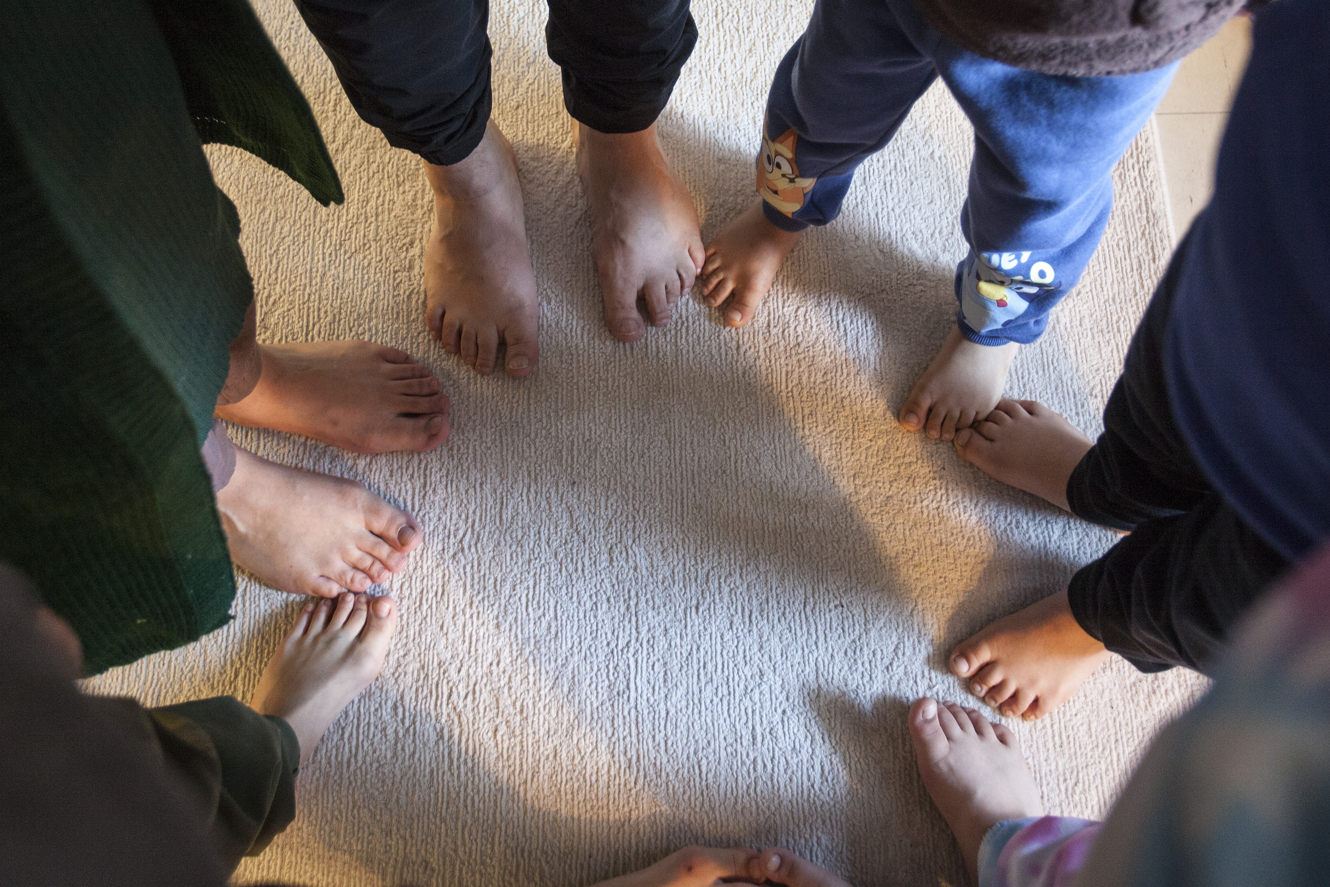 A family stand in a circle, displaying their feet
