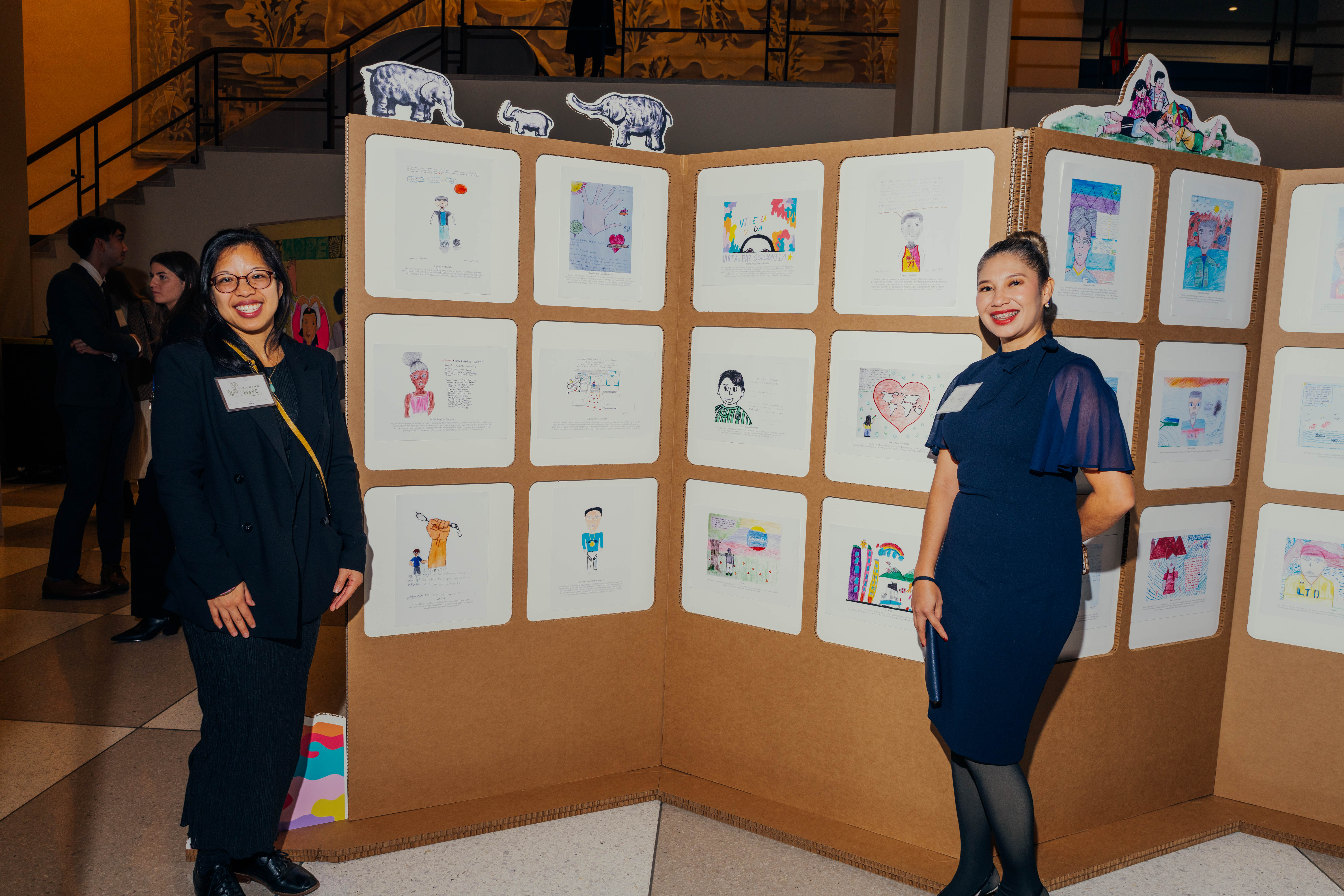 two women standing on either side of a photo gallery on vertical display board with two women 