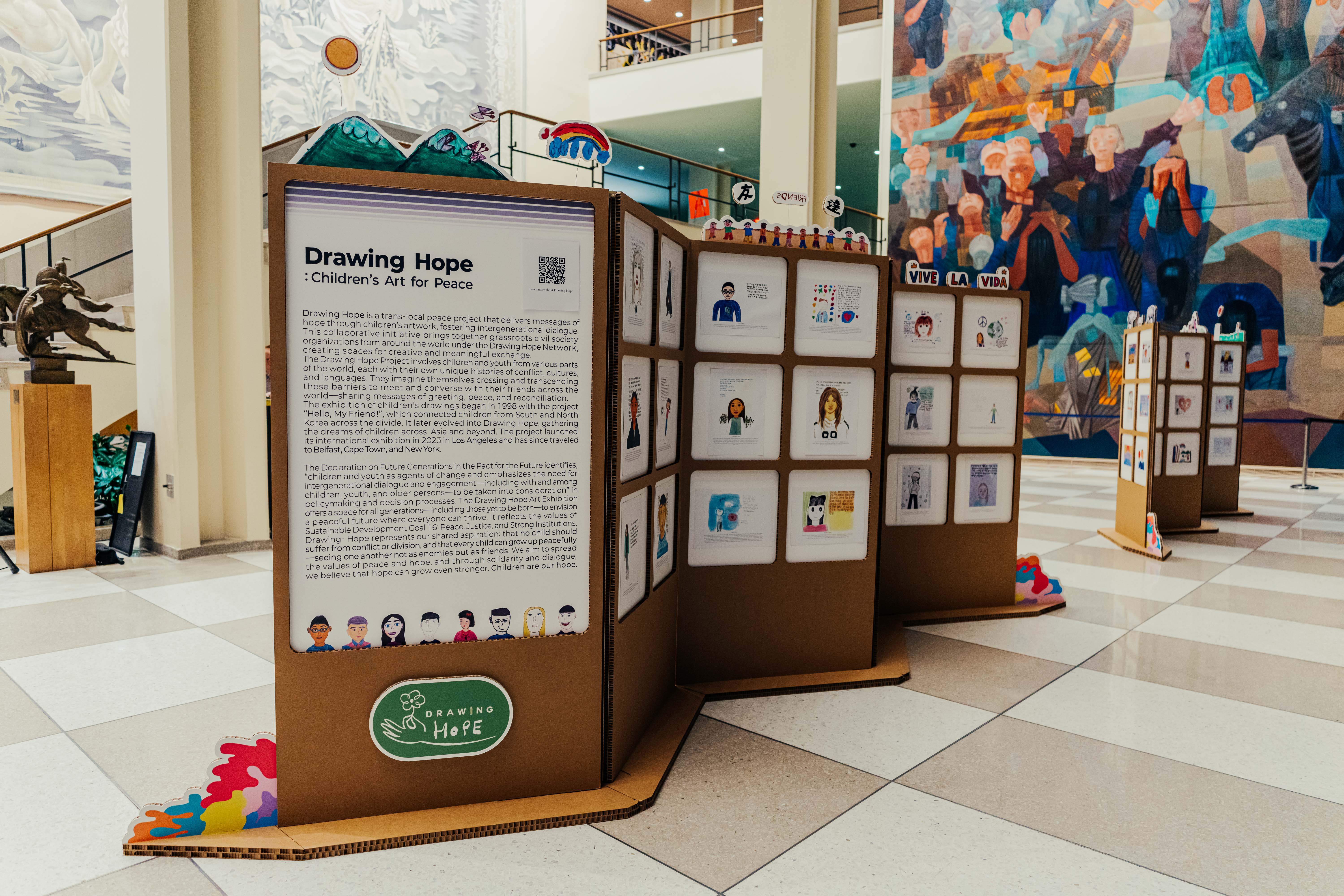 vertical panel of children's artwork stand inside large room