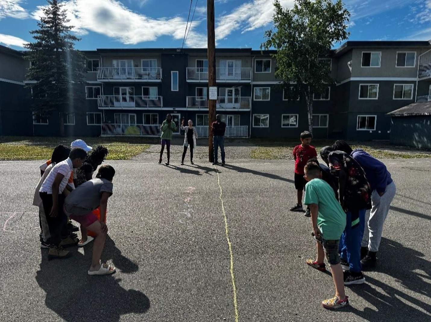 A group of children playing a game in front of an apartment complex