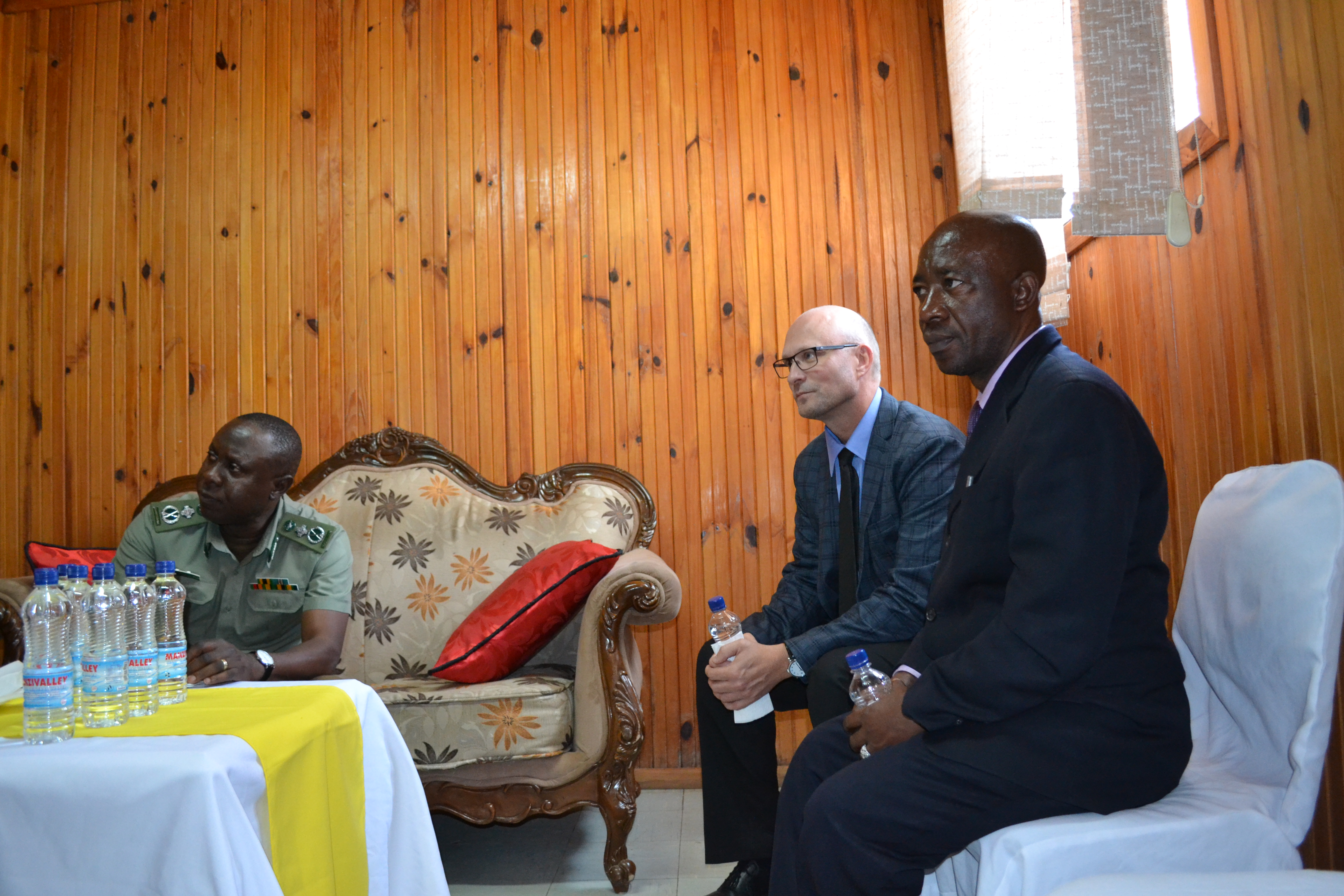 three men in suits sitting at a table looking thoughtfully at someone behind the camera