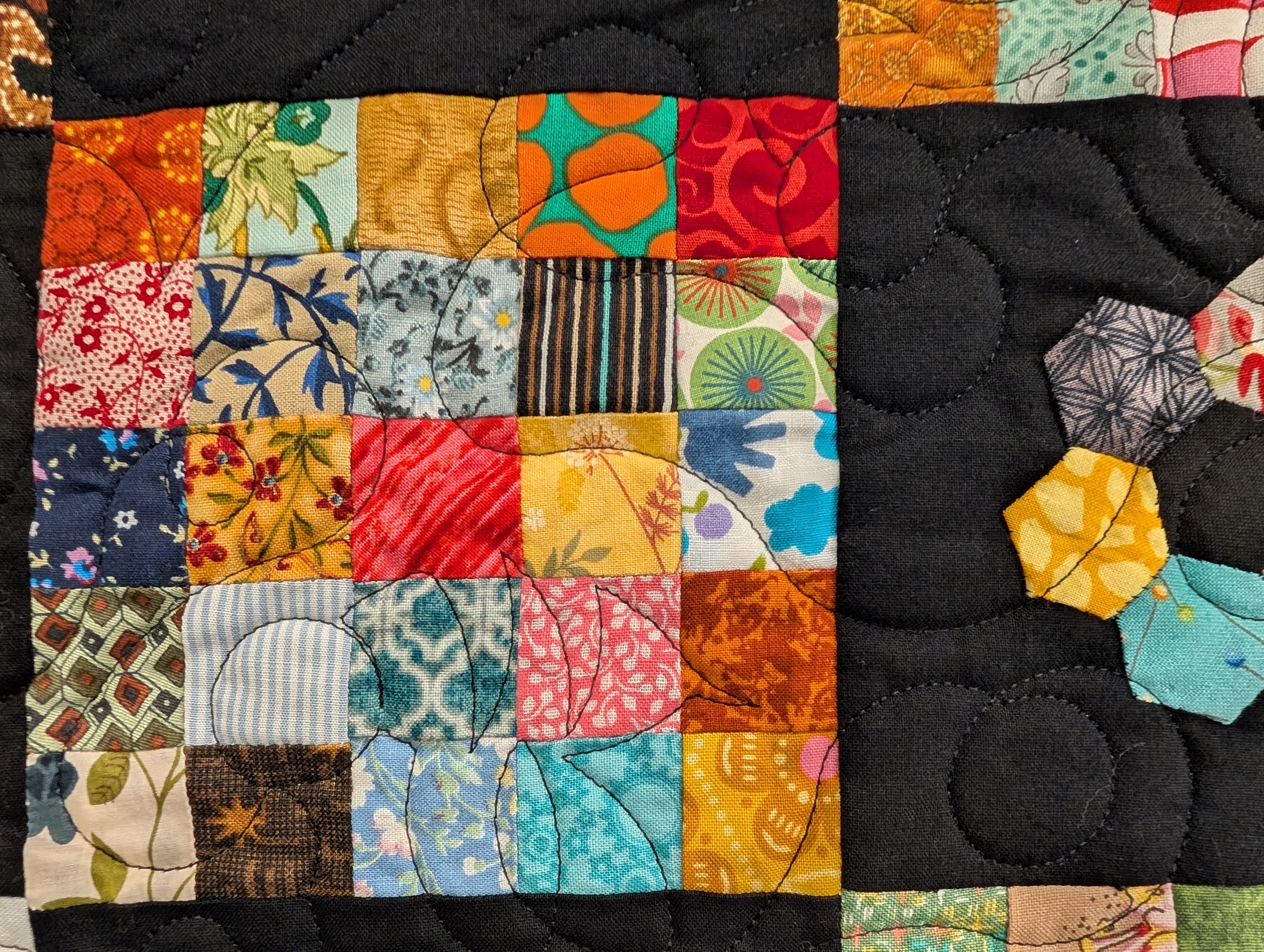 postate stamp quilt closeup with lots of different coloured 1 inch square pieces of cloth