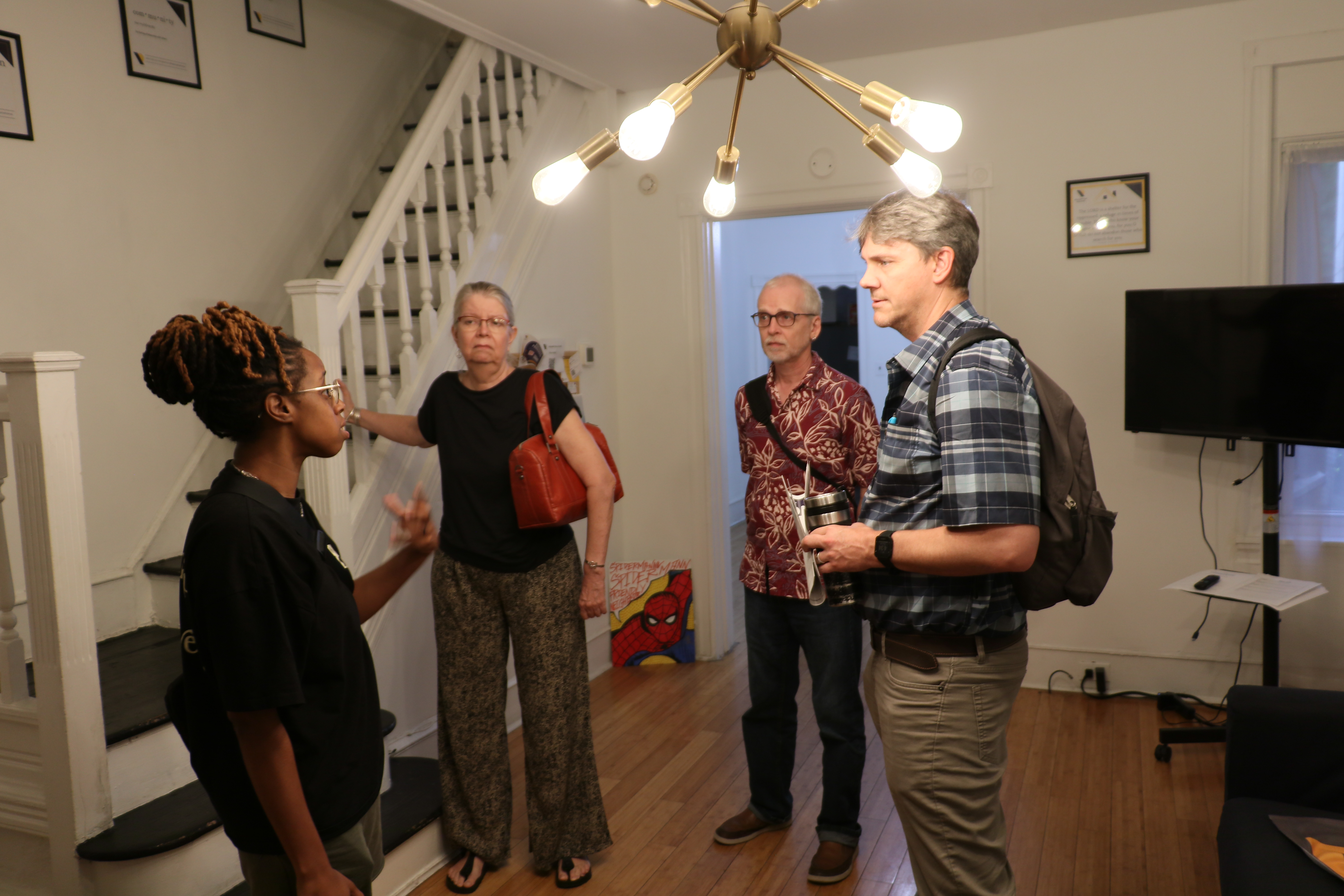 four people stand in a living room talking