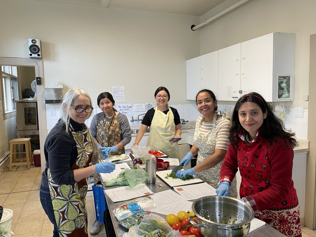 A group of women in a kitchen smiling for a photo