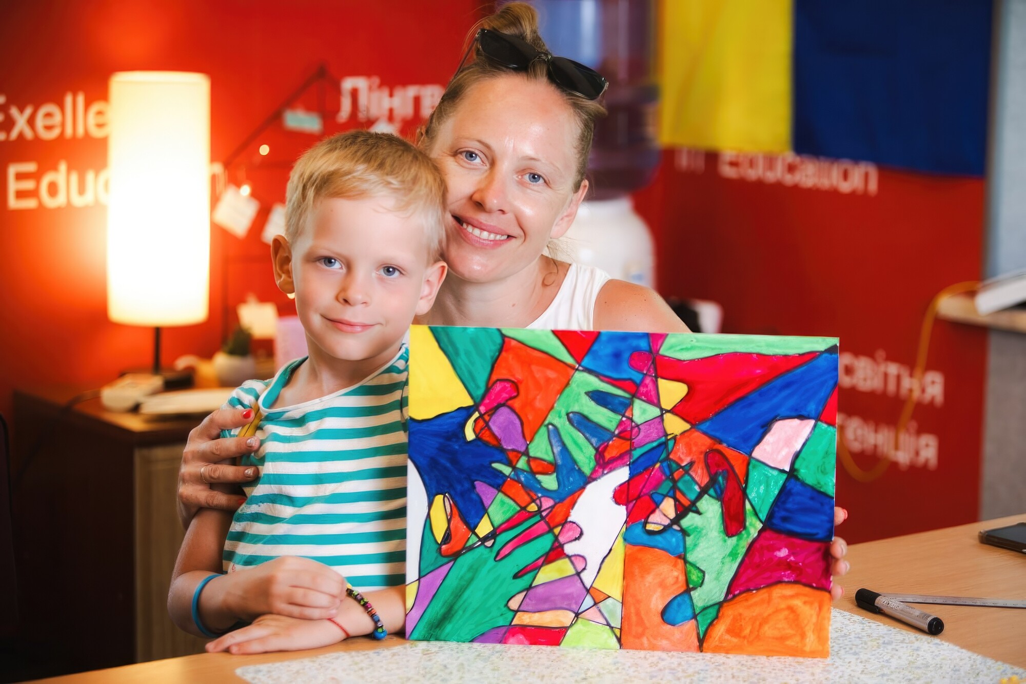 a mother and child pose with a colorful art project