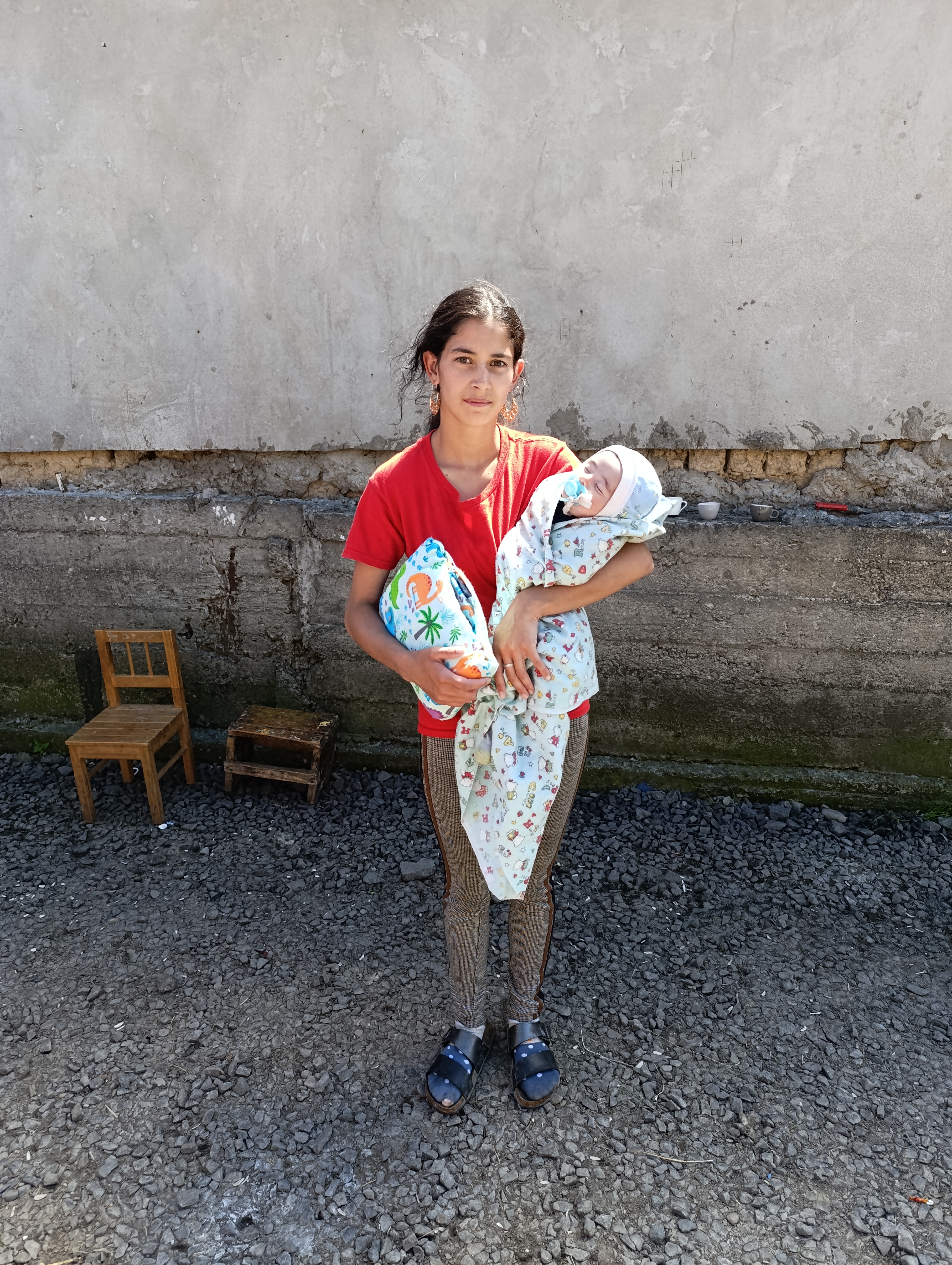 A woman in Ukraine stands with her baby and material resources distributed to her by an MCC partner. 