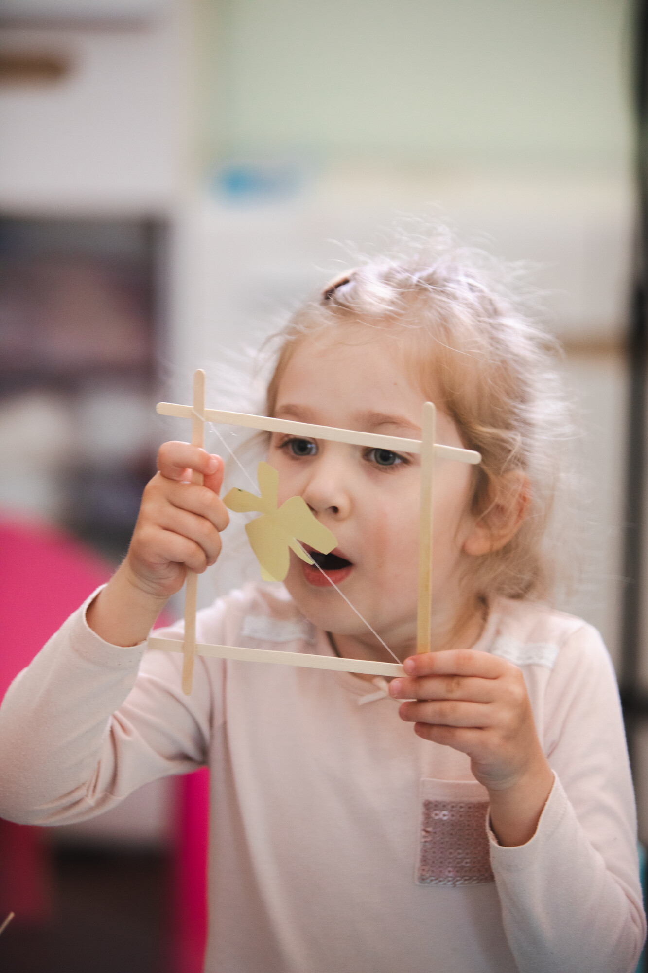 child blows bubble through square made of popsicle sticks