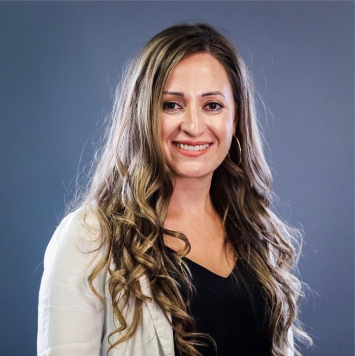 A woman with long hair wearing a black shirt and grey cardigan.