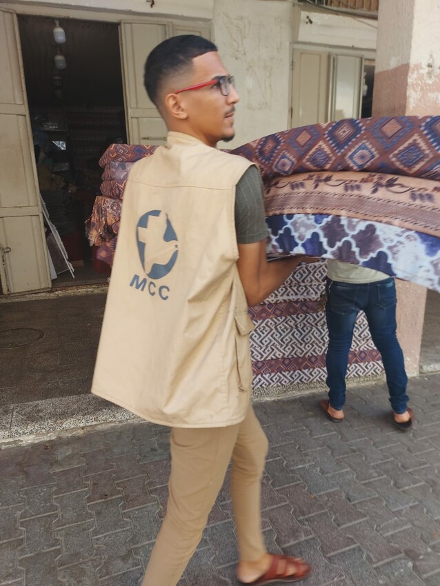 Firas Hamlawi, a volunteer with  Al-Najd Developmental Forum, an MCC partner in the Gaza Strip, helped distribute mattresses to families in need because of the October 2023 Israeli military bombardme