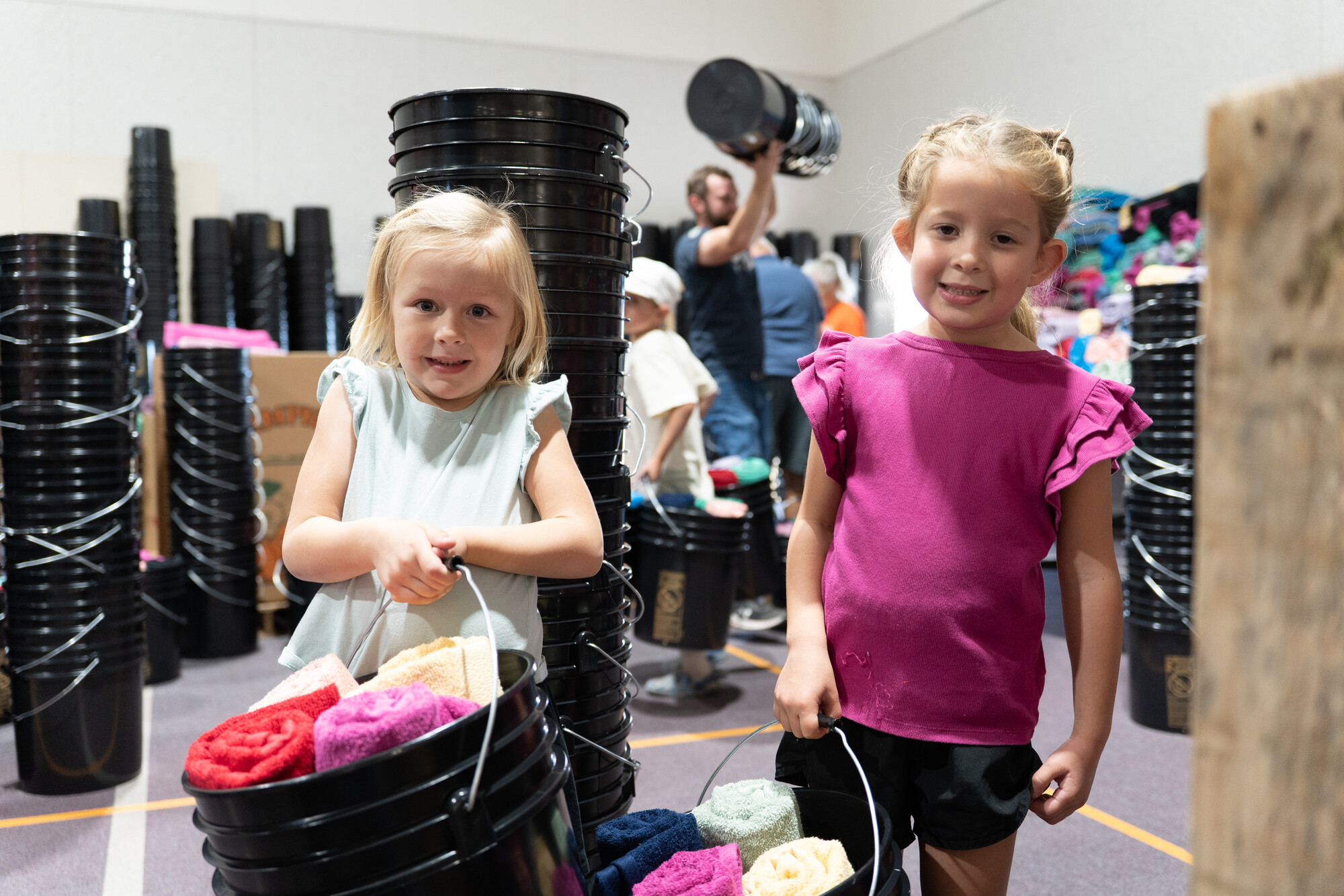 Hazley Cillers and Riley Miller, both 5 years old, carry buckets filled with essential hygiene items during Pleasant View Mennonite Church's fourth annual relief kit packing event.