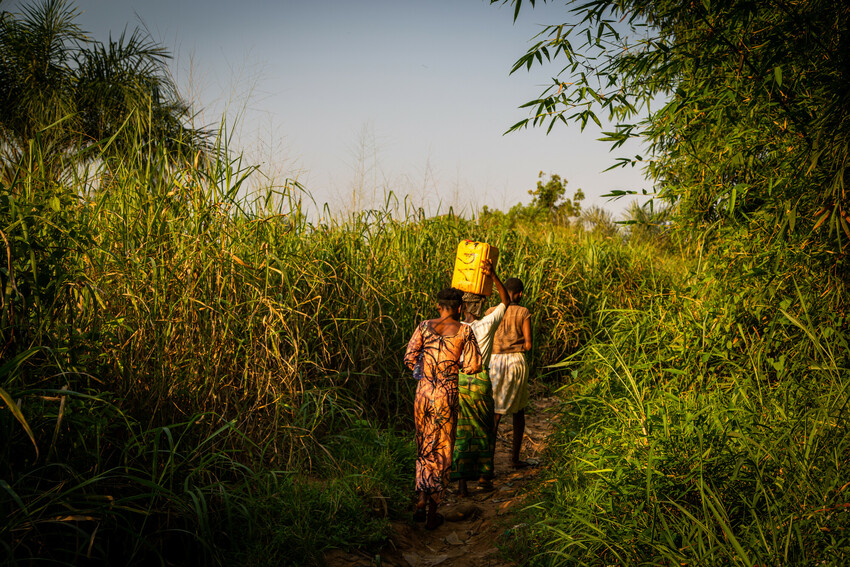 Germaine Kambundi and two of her daughters walk toward the spring where they used to collect water before the new borehole was built. The path becomes steep and treacherous.
