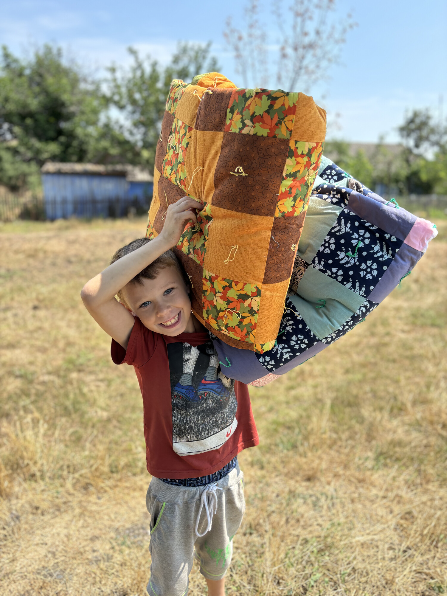 A young boy* holds MCC comforters distributed by MCC partner Association of Mennonite Brethren Churches of Ukraine (AMBCU). The distribution was held in a village on the border of Ukraine's Kherson an