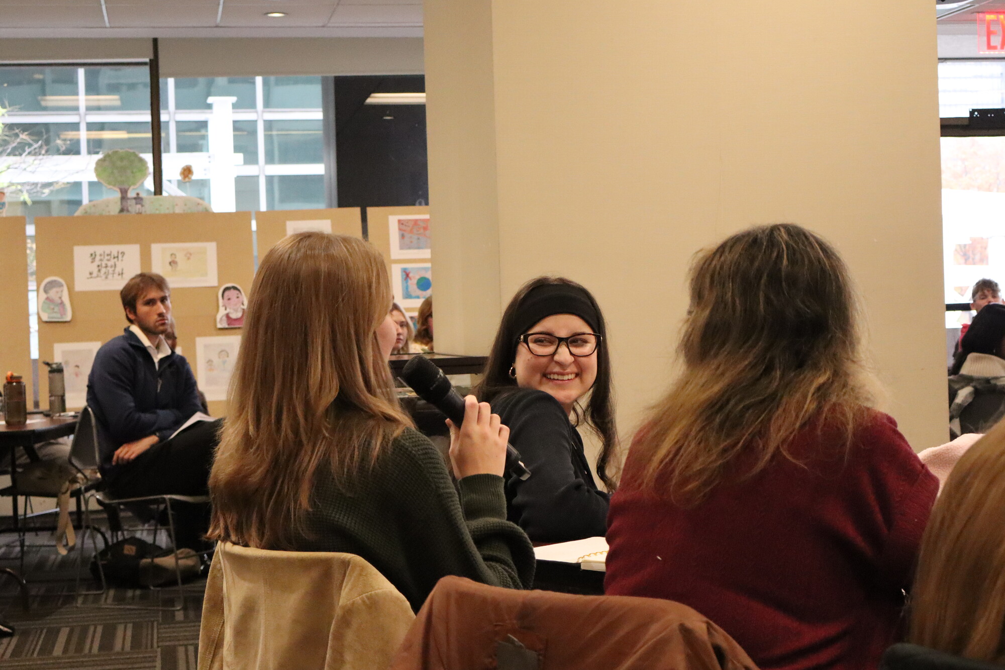 Participants sit together during a discussion session at the 2025 UN Student Seminar in New York City. Lily Corkhill speaks into a microphone, while Sofia Herrera Varela smiles in response.