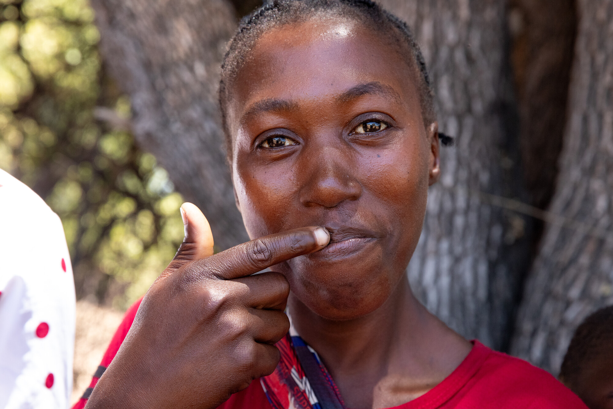 Mercy Munsaka demonstrates the use of a lip balm made with wax from the youth beekeepers' group's hives.