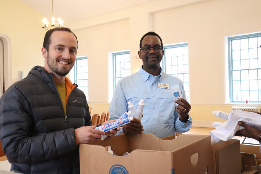 Dan Zook (left), MCC finance associate and accountant, and Andrew Bodden (right), MCC East Coast program director, hold up prison care kit items at the 2024 MLK Service Day event in Philadelphia, Pa.
