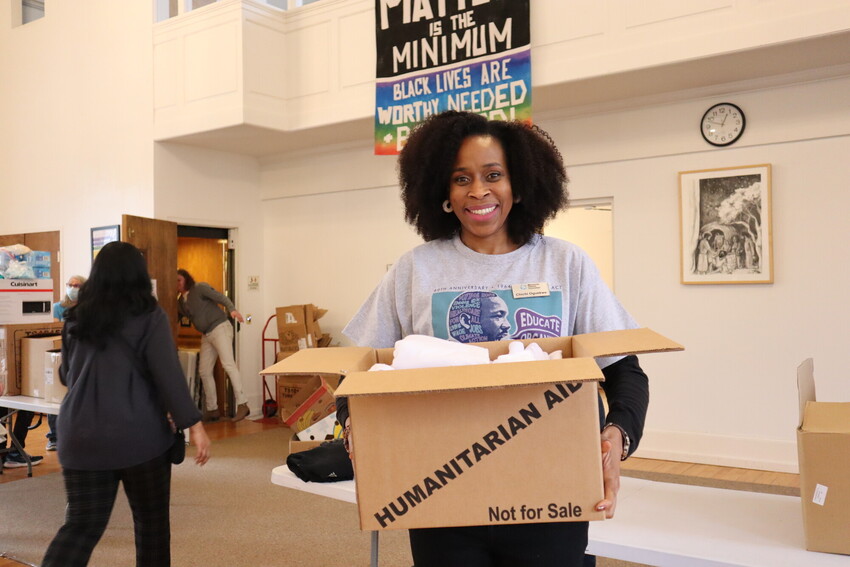 ChiChi Oguekwe, Philadelphia Program Coordinator for MCC East Coast, holds a box labeled ‘humanitarian aid’ at the 2024 MCC MLK Service Day event at Germantown Mennonite Church.