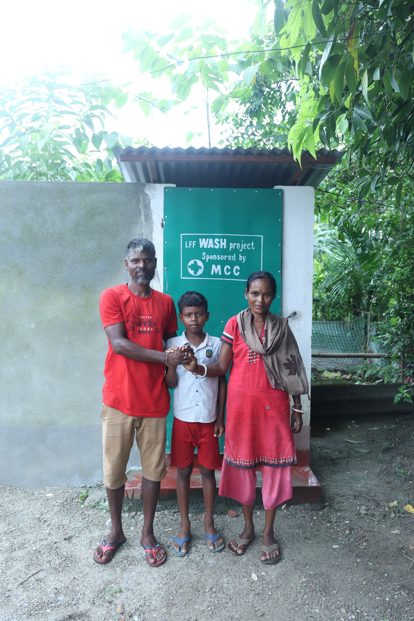 Sanjay Minj, left, with his wife, Lalita Minj, and son Ansh Minj, stands in front of their toilet, which has done so much to help them live healthier lives.