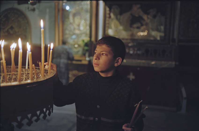 Milade Thalgieh (pictured in 2001) lights a candle in Bethlehem’s Church of the Nativity, West Bank, Palestine weeks after his brother Johnny, 17, who wanted to be a priest, was shot and killed while