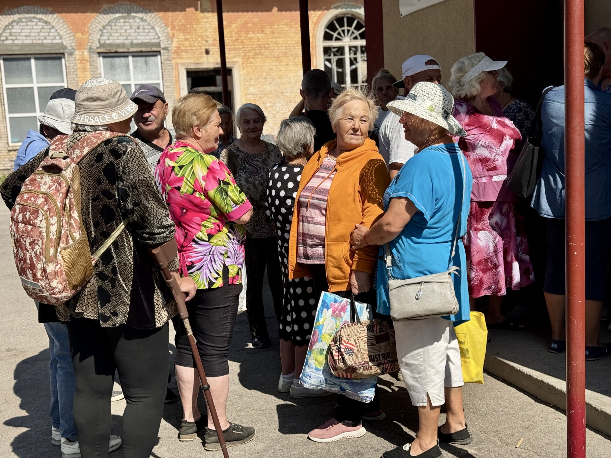 Waiting in line for water and the dining room to open,Valentina,* right wearing a hat, chats with friends she has made during her visits to the New Life Charitable Fund (New Life).
*Last name withhe