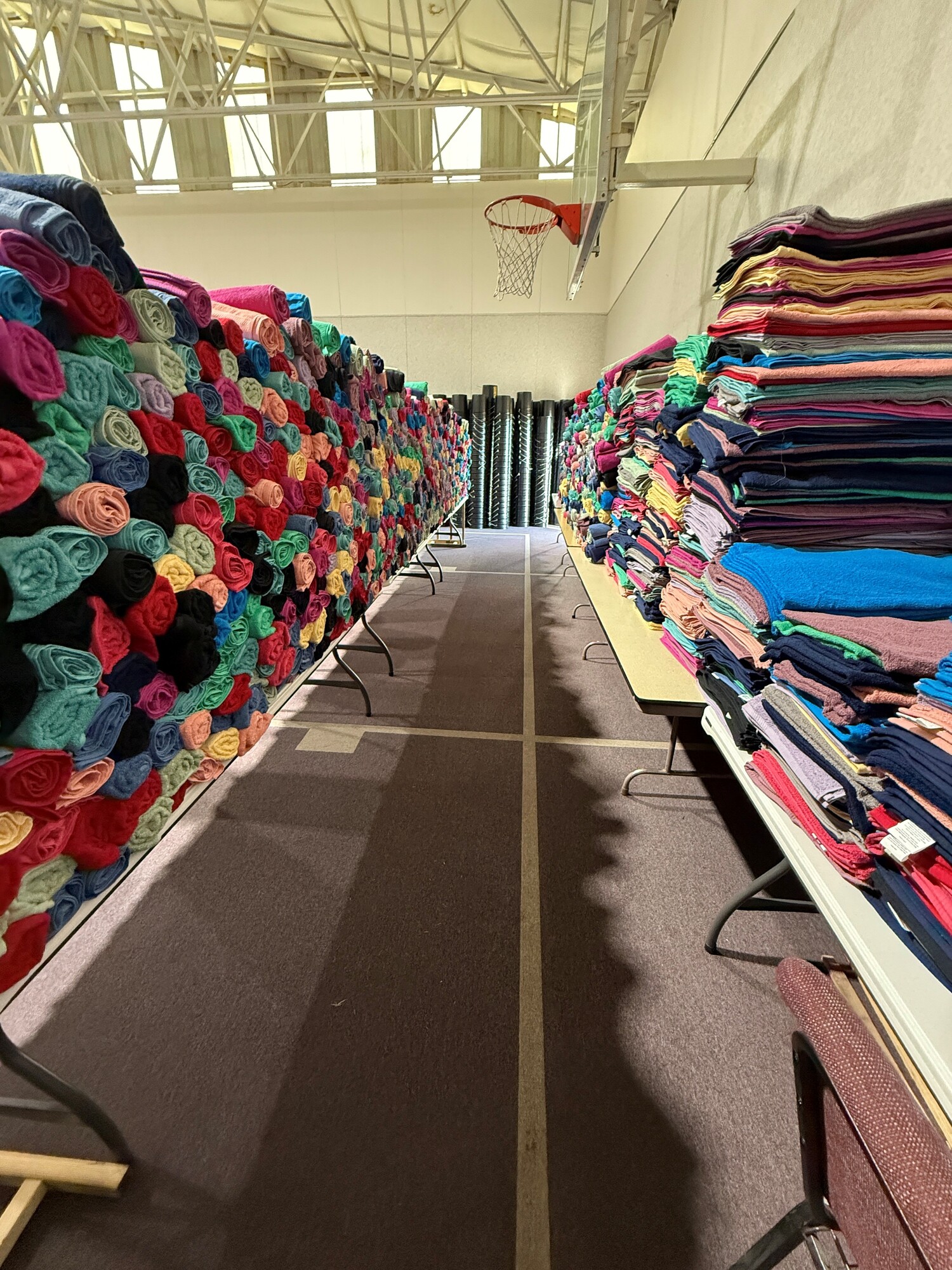 Rolled (left) and folded (right) towels are stacked on tables in Pleasant View Mennonite Church's gymnasium, during the church's fourth annual relief kit packing event.