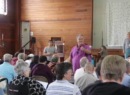 An auctioneer in a purple shirt stands in front of a crowd