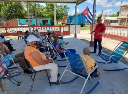 RS119544_Ancianato 4.jpeg A man in a red shirt speaks to a group of elderly Cubans who are sitting in front of him.