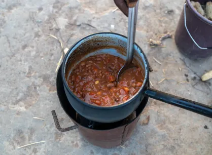A pot of beans cooking over a small outdoor stove