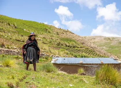 rs115834img1557-lpr.jpg A woman standing in a hilly landscape next to a small building
