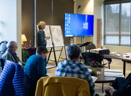 A woman facilitating a group workshop with a few participants pictured.