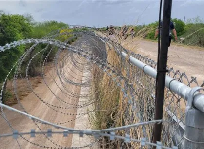 Barbed wire on top of chain link border fencing