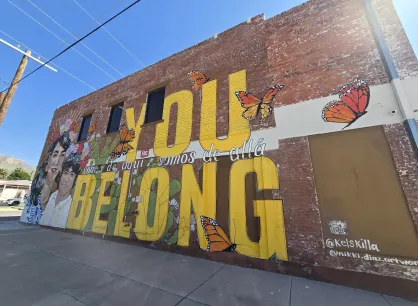 Mural of brick wall, with text "You belong, somos de que somos de alla"