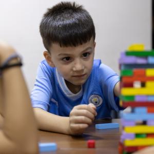 A child in Syria plays with Jenga blocks at a table of his peers. 