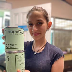 A young woman holding up cans of MCC meat